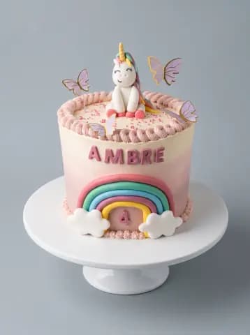 Gâteau rose avec licorne et arc-en-ciel sur un présentoir blanc